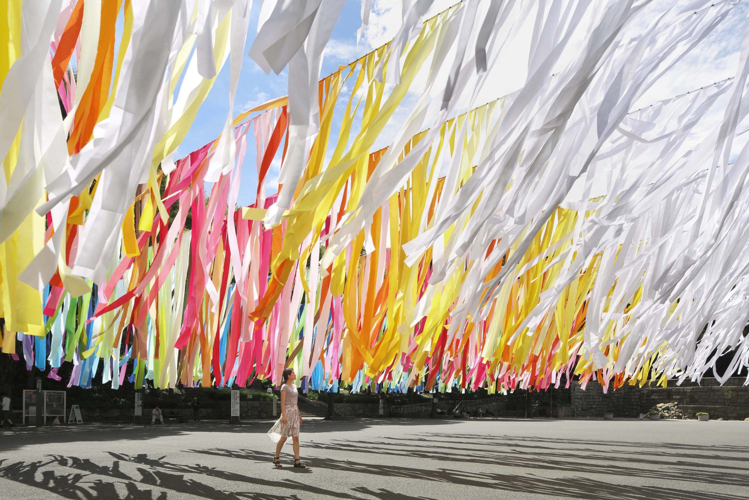 Het derde kunstwerk in de 100 colors serie van Emmanuelle Moureaux. Een vrouw loopt onder vele kleurrijke lappen van stof in de buitenlucht.