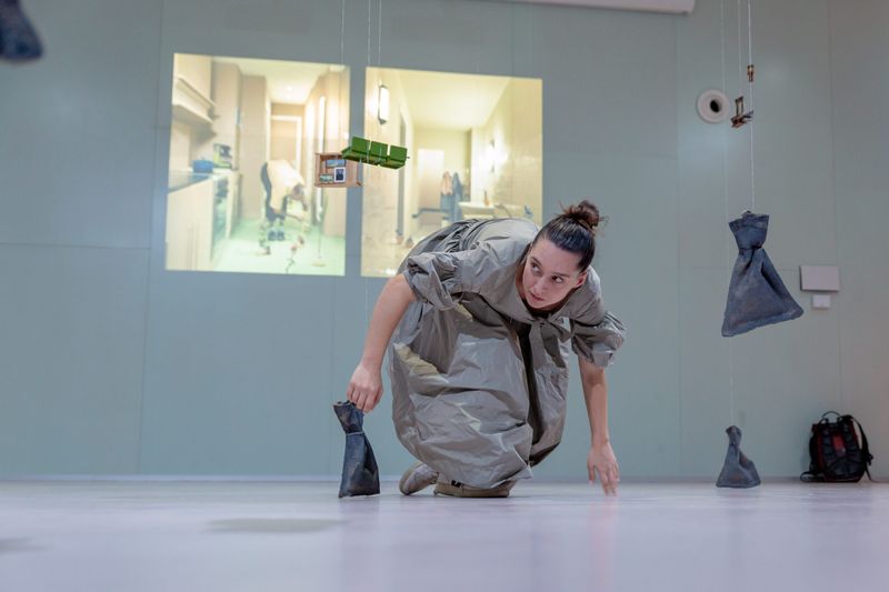 Een vrouw danst door de hangende miniatuur-installatie 'Alleen met Iedereen'. Ze hurkt en kijkt onder de installatie door.